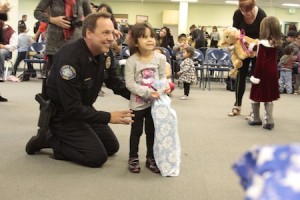 Local resident Chloe Estrada, 4, in her first year at the club, poses with a police officer with her new blanket.