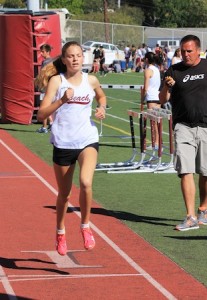  Janie Crawford wins the 800 at the Godinez dual meet while Coach Steve Lalim looks on with stopwatch in hand.