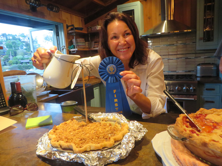 Wendy Canfield about to pour toffee sauce on her first-place fruit pie; hers was selected from a coterie of savory and sweet entries.