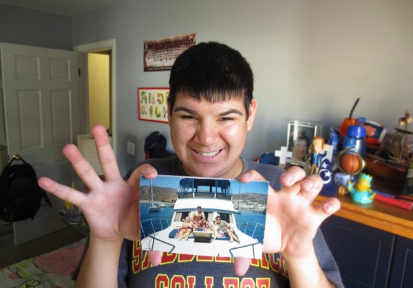 Local Andrew Arredondo, admitted to the UCLA Pathway Program for students with developmental disabilities, displays a family photo of a boat that he aspires to own. Photo by Marilynn Young