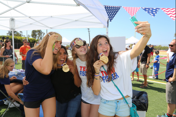 Makenzie Fischer, left, and friends show off real and faux gold medals at the welcome party for the two local Olympians. photos by David Nash.