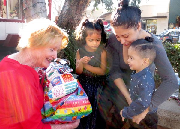 Chris Loidolt, left, brings gifts to Maggie Ladislao Ramirez,22,  and her two young children, Arianna Purez, 6, and Cartur Ladislau,2, who are recipients of the Adopt-a-Family Program in Laguna Beach on December 10, 2016 Photo by Marilynn Young