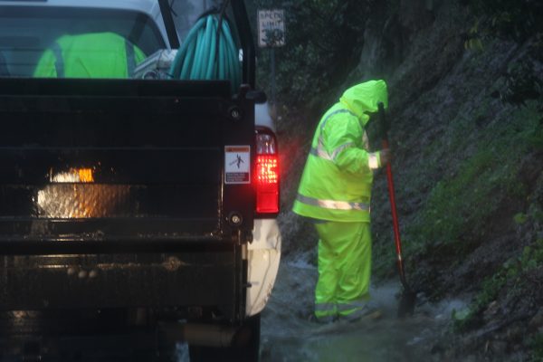 A public works crew clears rocks from a drain on Bluebird Canyon Road.