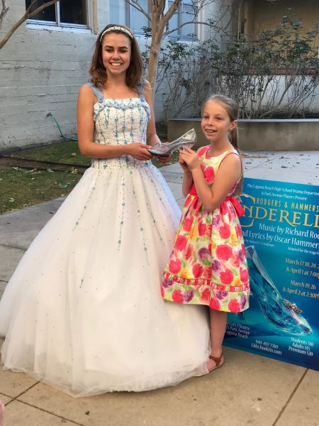 Katie Baker, right, surrenders the missing glass slipper for tickets to “Cinderella,” which concludes this weekend at the LBHS Artists’ Theatre.    