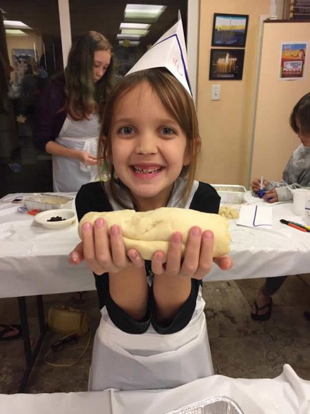 A young challah baker displays her handiwork. 