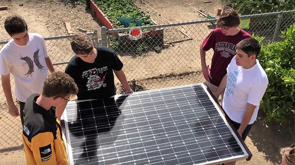 Members of the LBHS Solar Club carry a solar panel to the TOW garden. Photo by Parta Perkins. 
