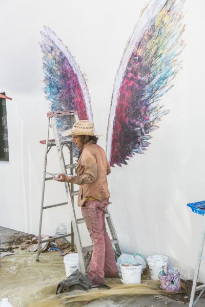 Artist Colette Miller finishing her only Orange County angel wings installation on a historical building in downtown Laguna Beach.Photo by Dondee Quincena .