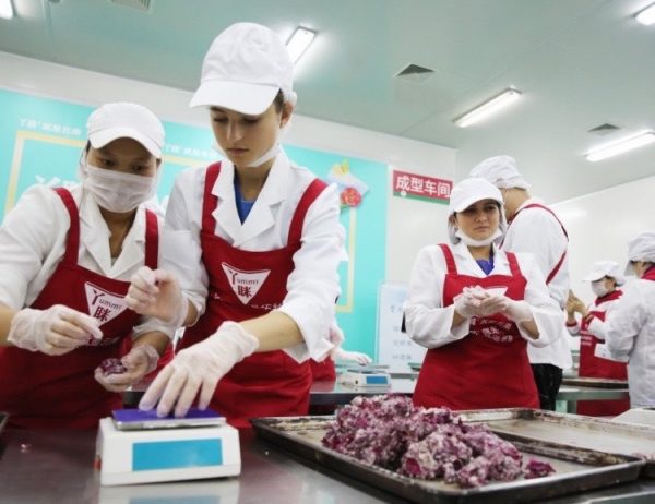 Charlie Hoffs, center, works in a cookie factory, one of many tasks she and U.S. teammate Kaylee Doty completed as a part of a nearly three-week contest in China.