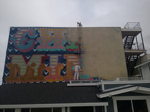 Painters in May paint over the short-lived “Charming” mural, installed by British street artist Ben Eine in 2015. Building owner Mo Honarkar’s promise of a replacement has yet to materialize. Photo by Brad Wood. 